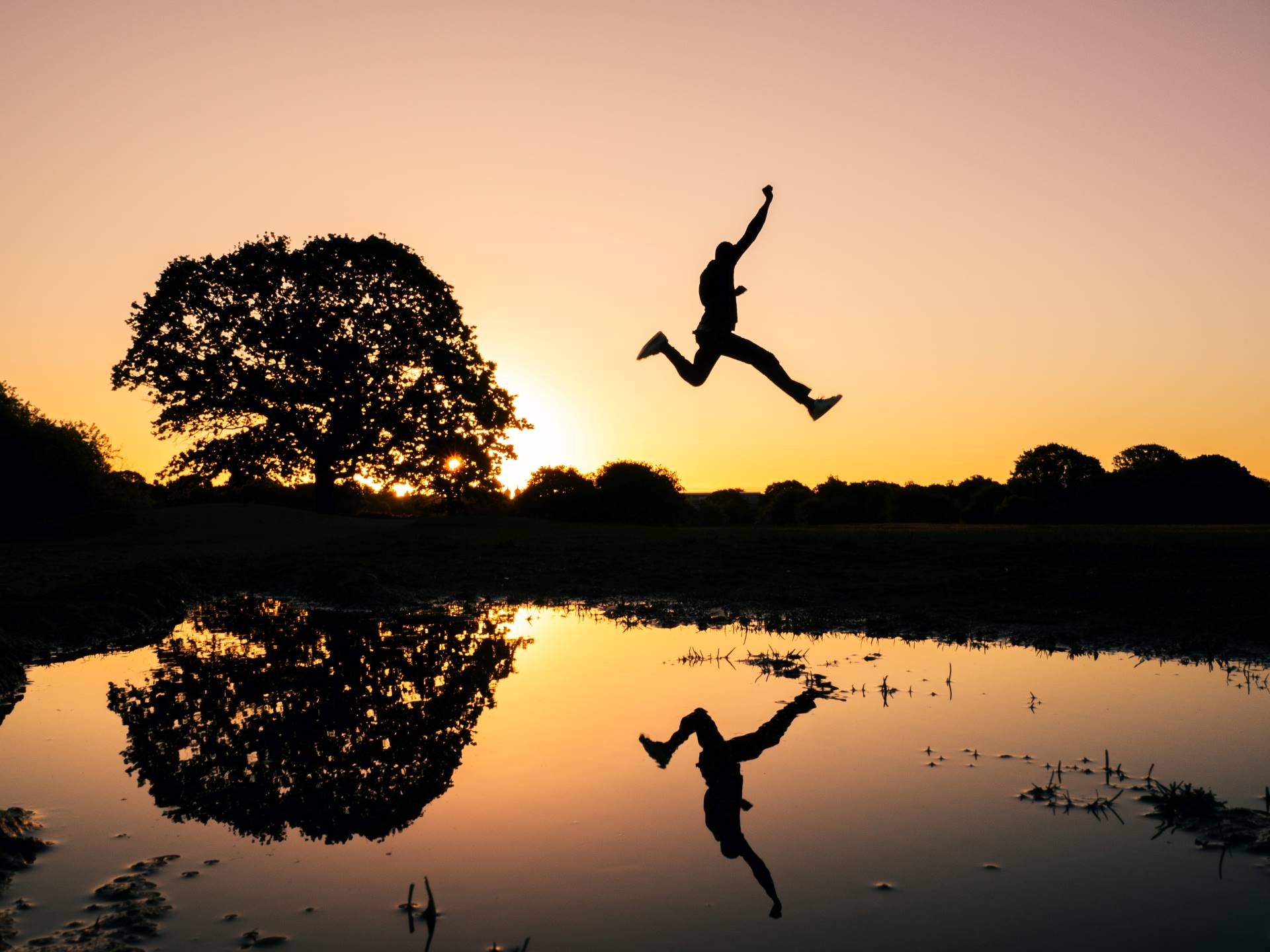 This is an image of a man jumping over a lake