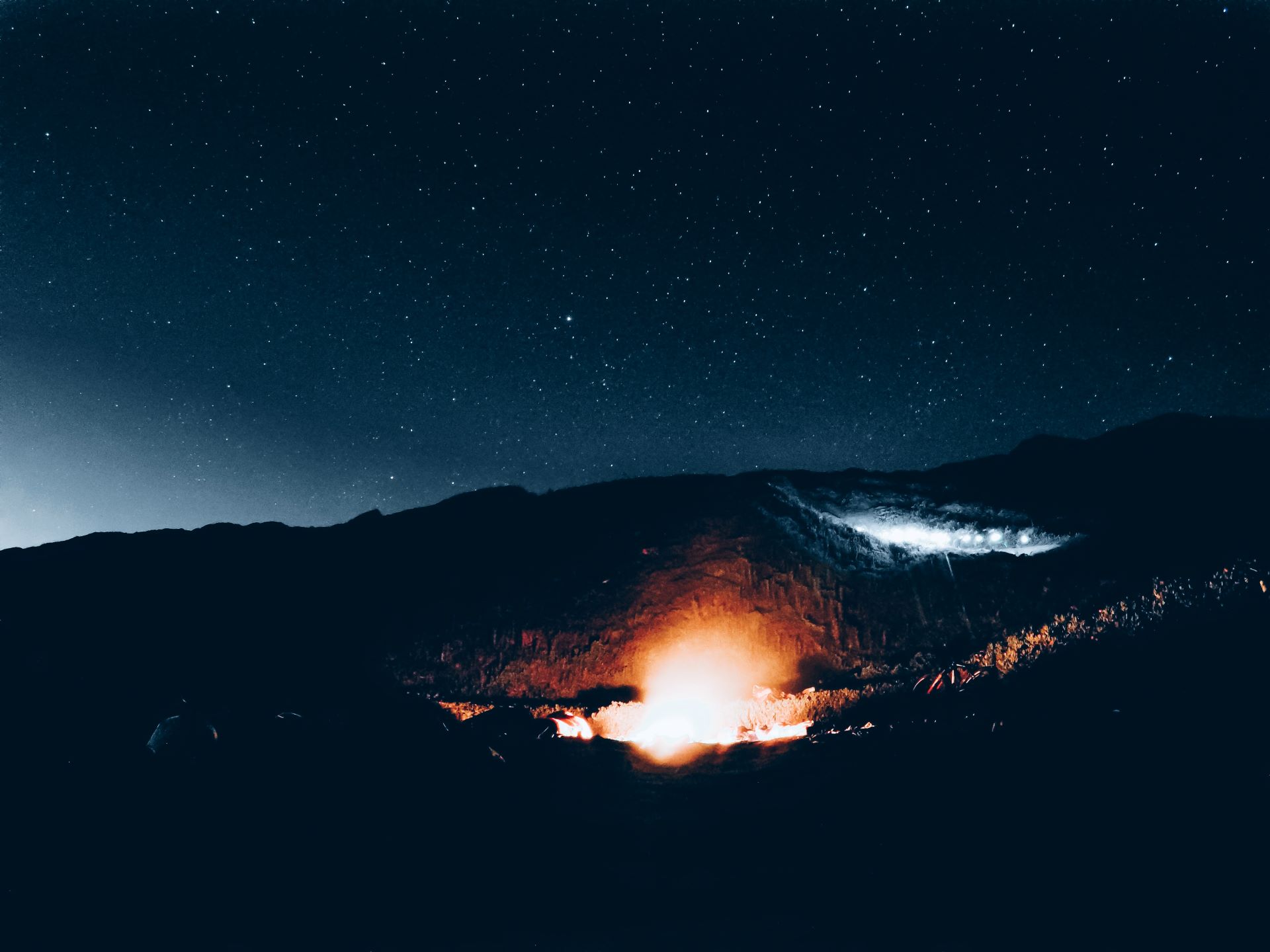 This is an image of a camp fire with the stars covering the stars