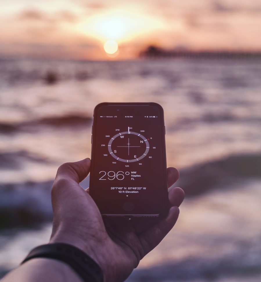 This is an image of a man holding a compass and pointing to the sunset