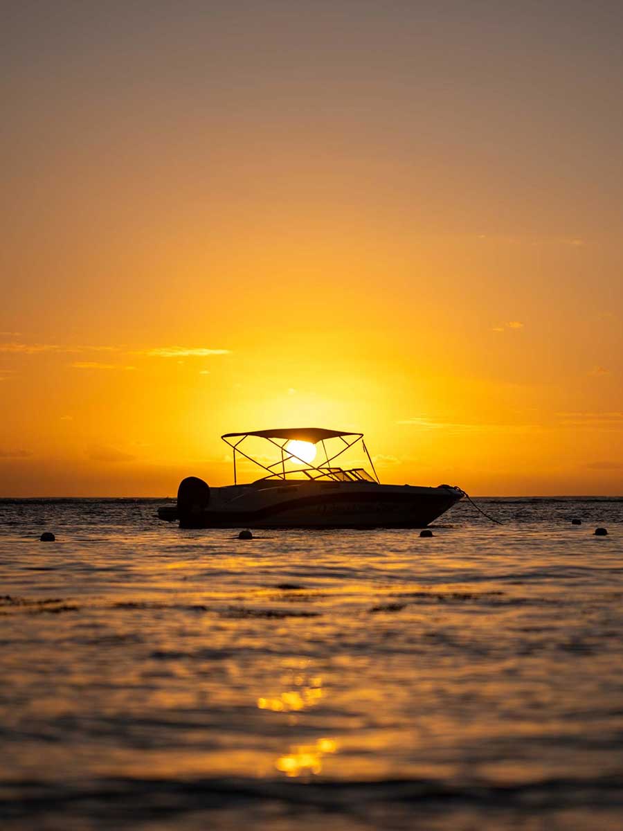 This is an image of a boat on the water with the sun set in the background