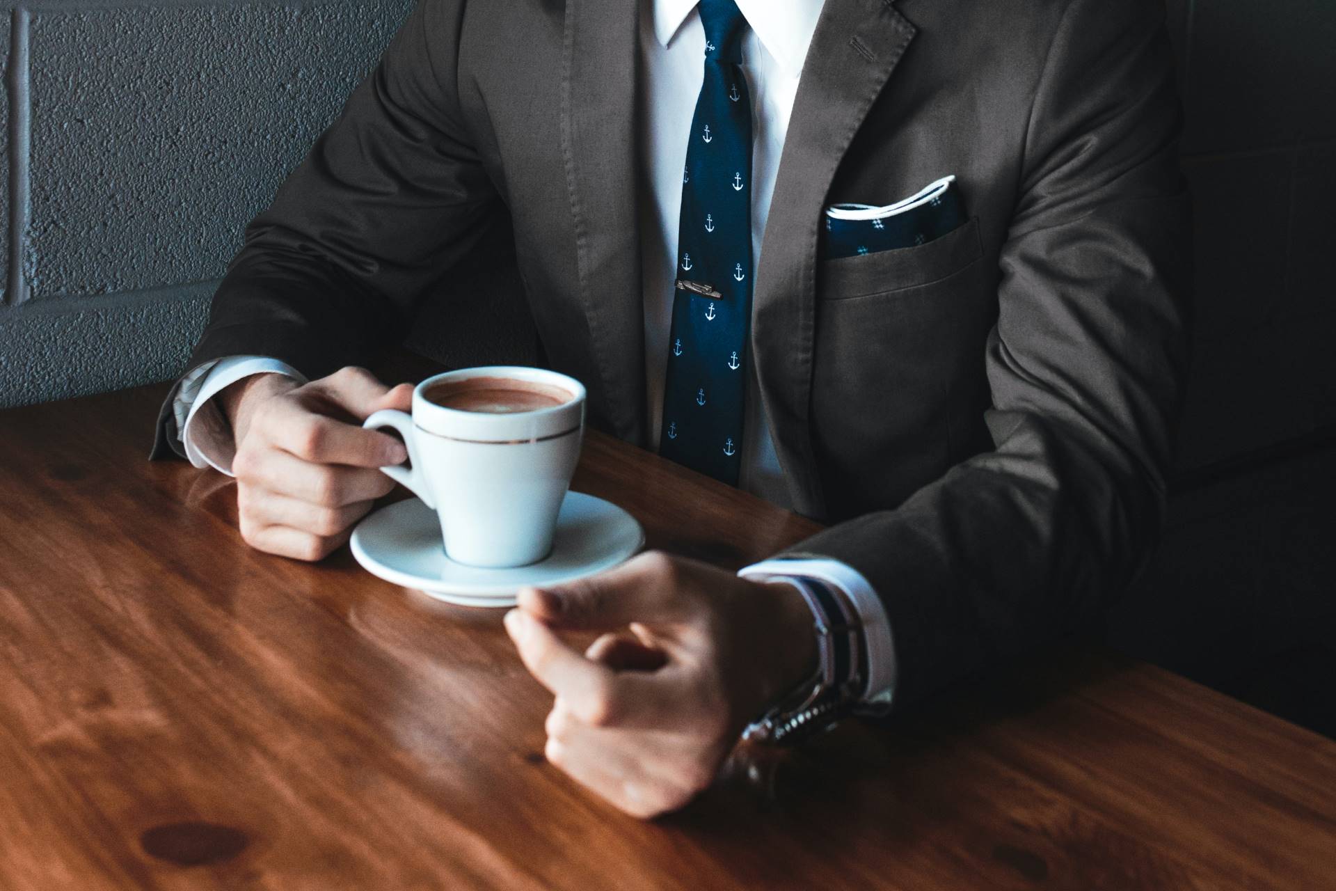 This is an image of a man in a suit that is drinking coffee