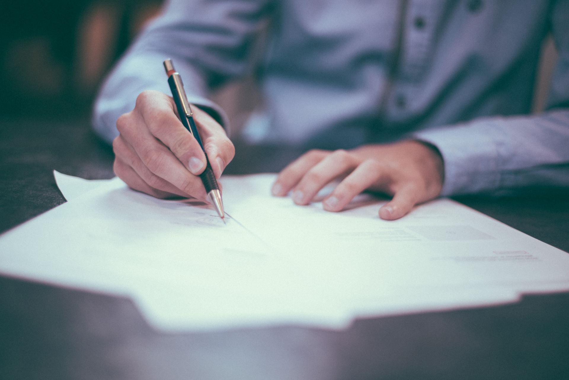 This is an image of a man writing on a piece of paper